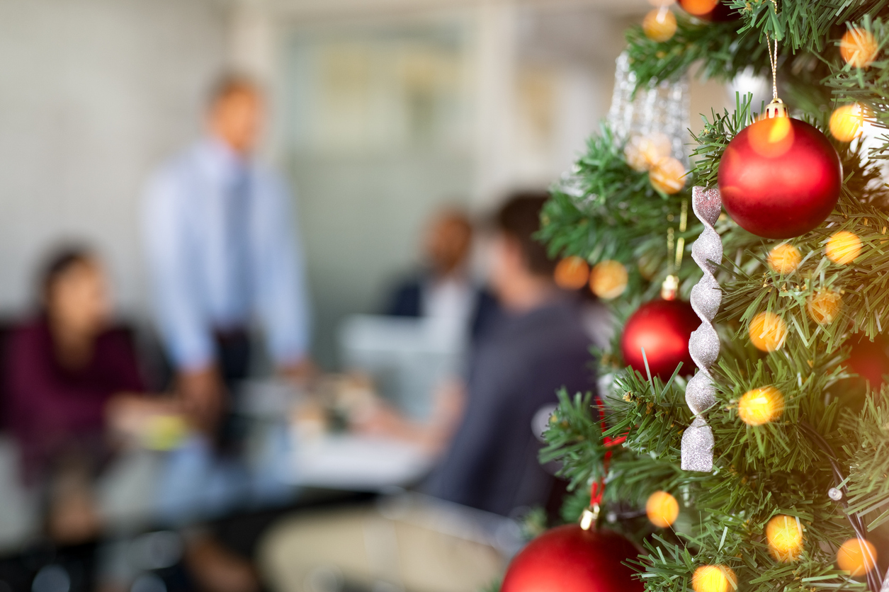 Close-up photo of an office Christmas tree, with a professional team in the background working on B2B holiday marketing plans.