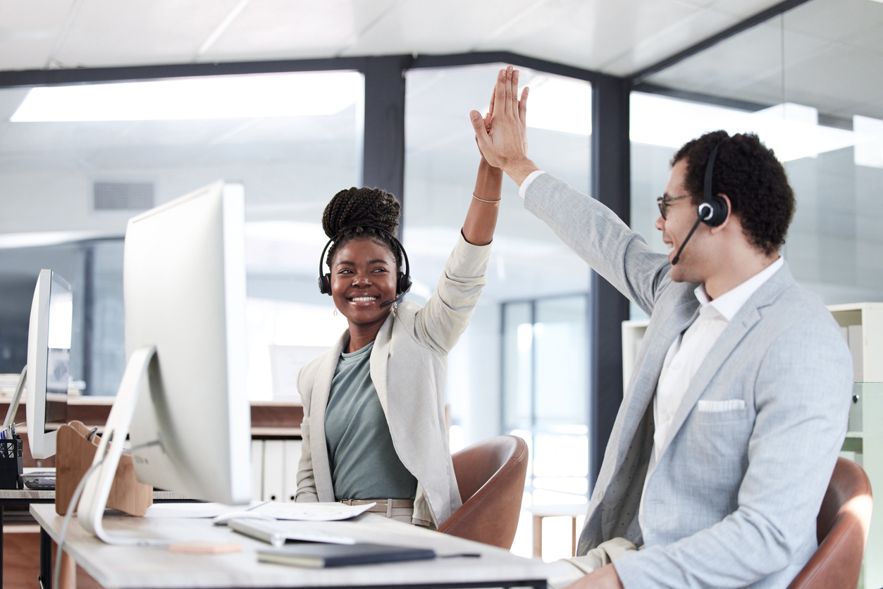 Two sales agents high-five after reaching customer service goals