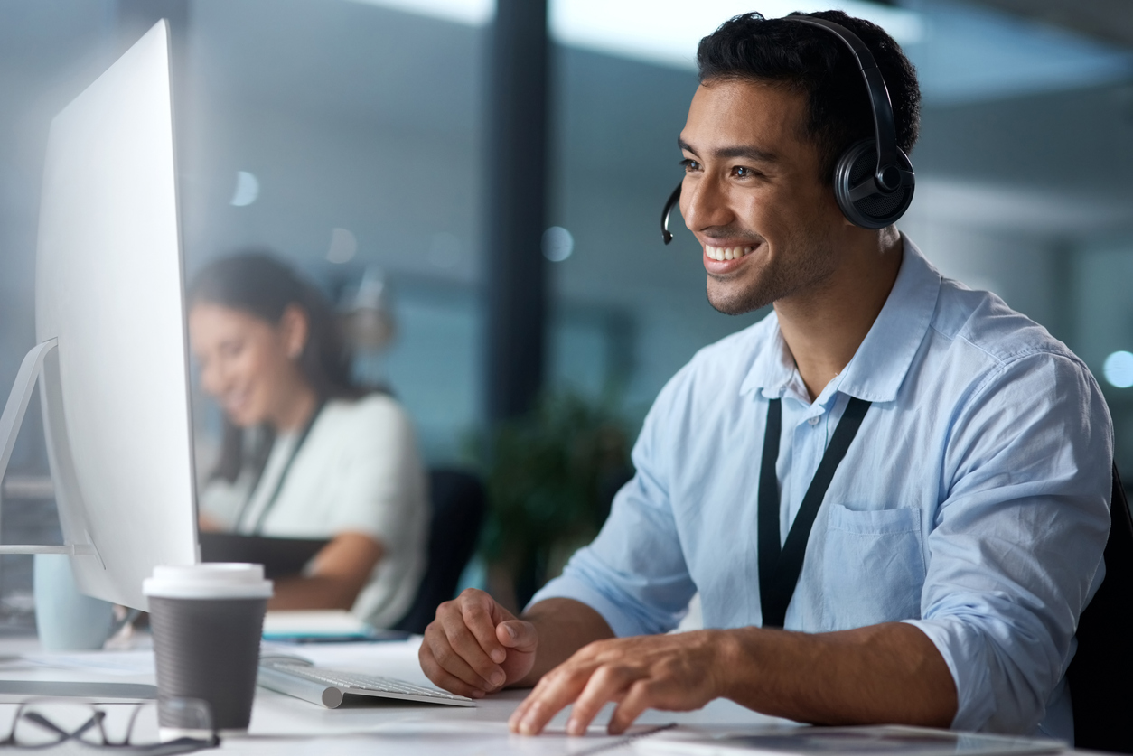 Telemarketing professional smiles while on a phone call with a customer.