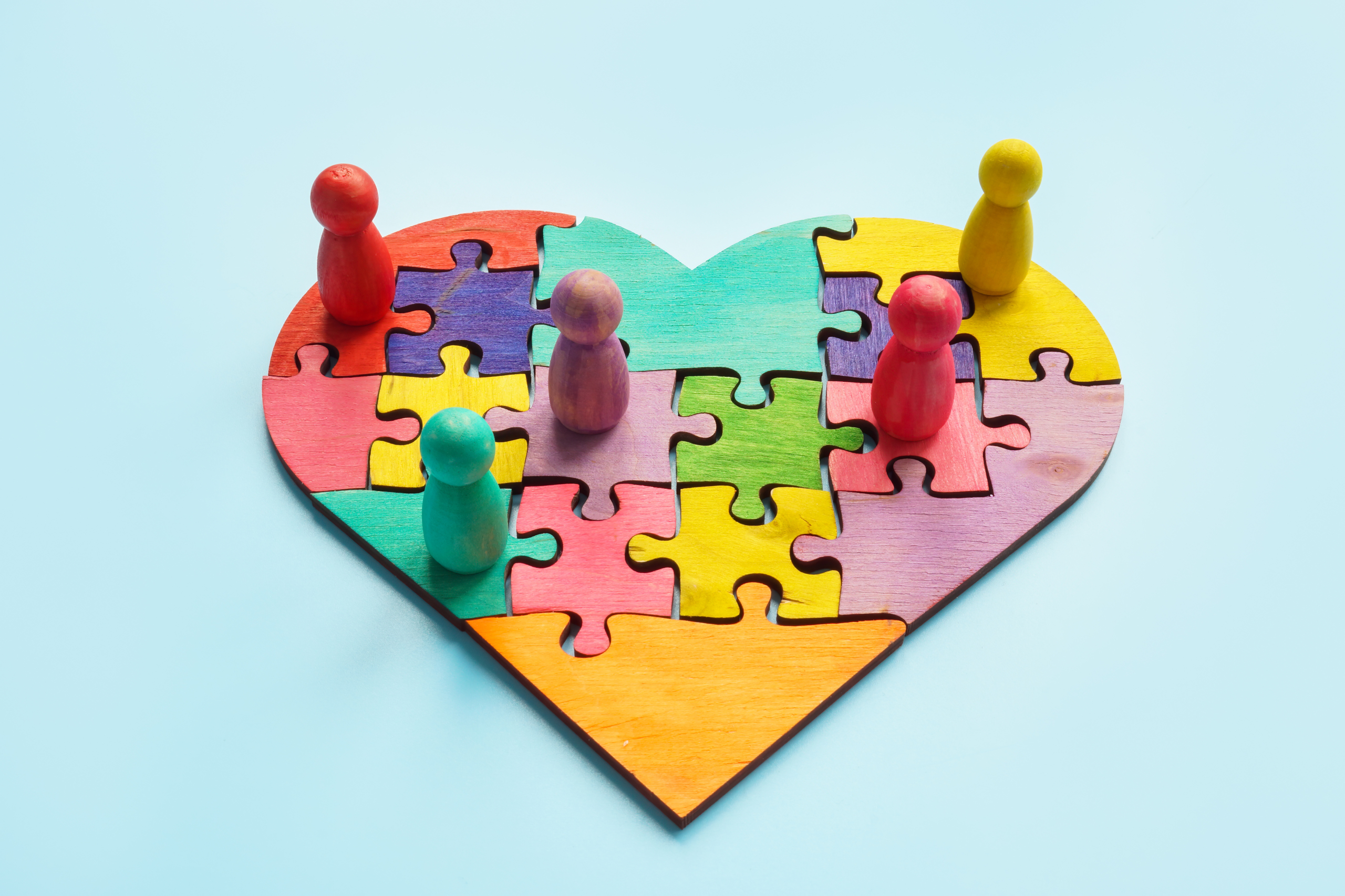 Togetherness and inclusion. A Puzzle heart and colored figurines.