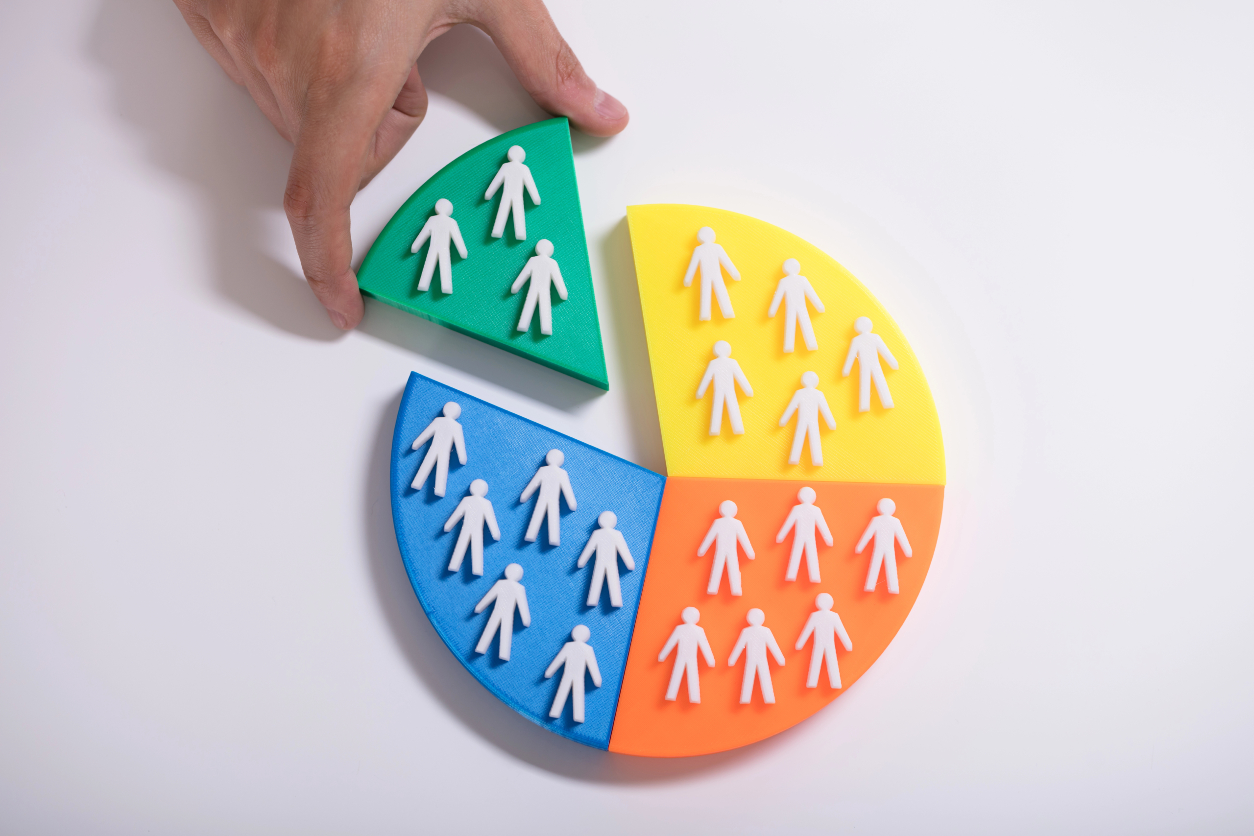 Hand pulling out a piece of a pie graph with human silhouettes, representing customer segmentation