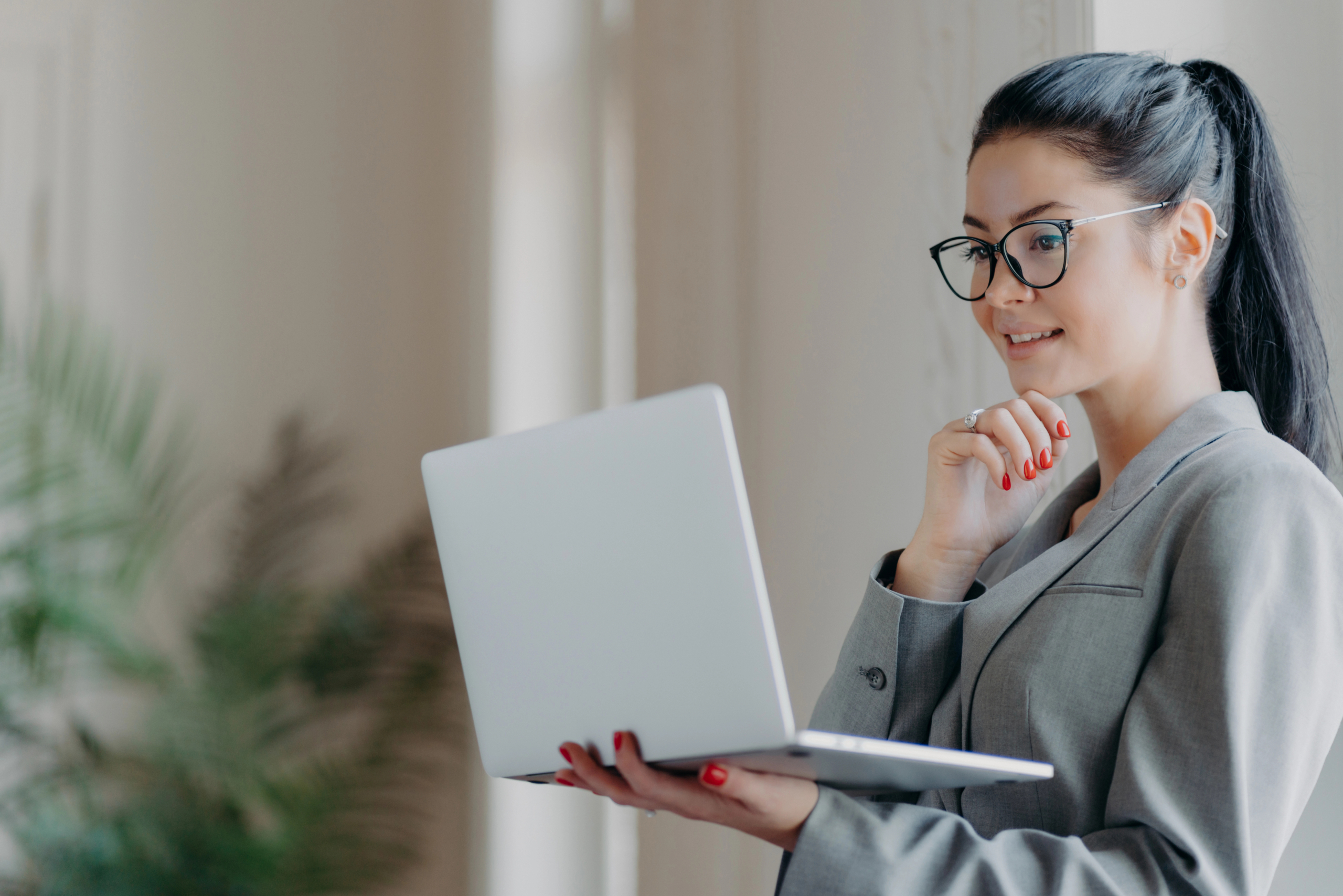 woman stands with laptop computer and looks pleased with website lead generation