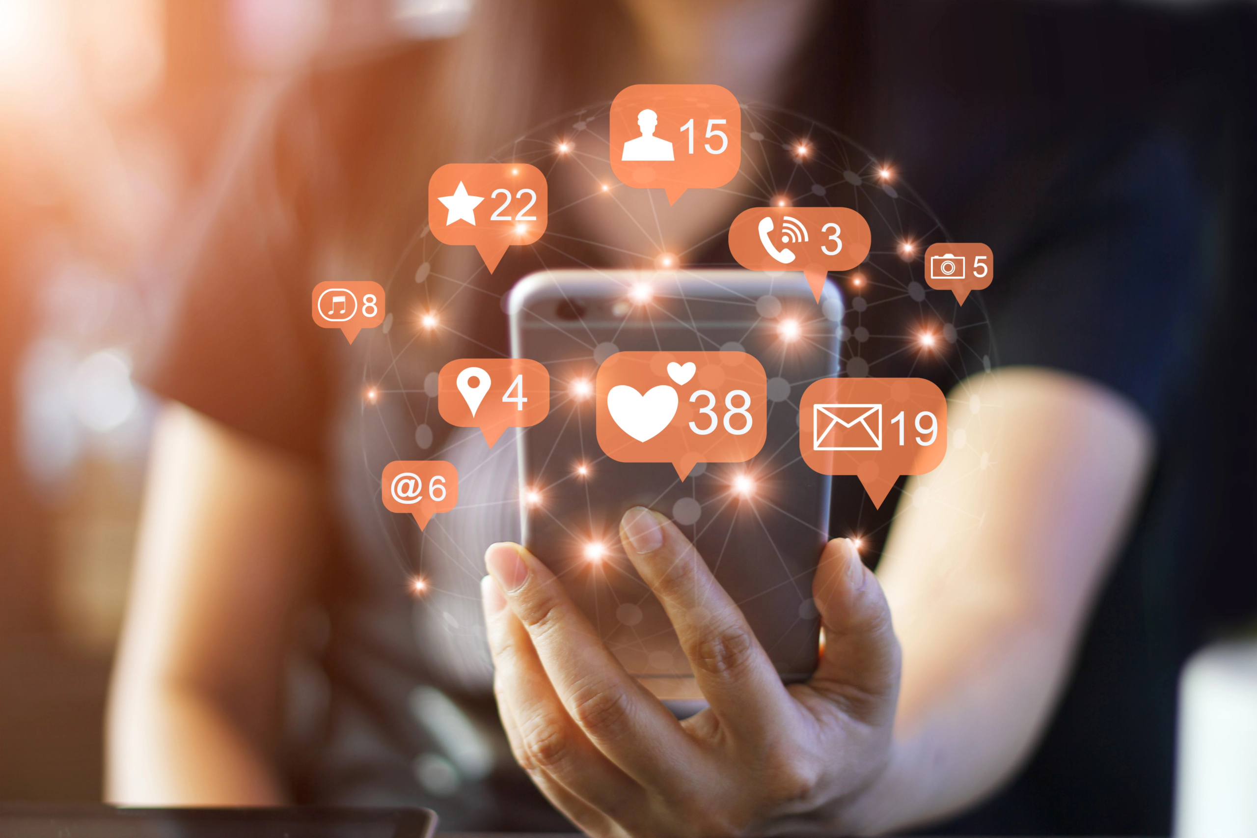 woman uses smartphone with media icons to represent b2b demand generation