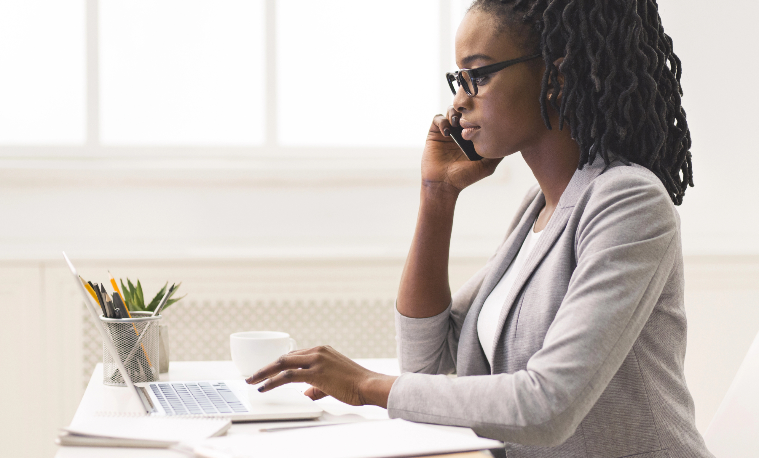 woman sits at desk with laptop computer and smartphone and learns about marketing mix optimization