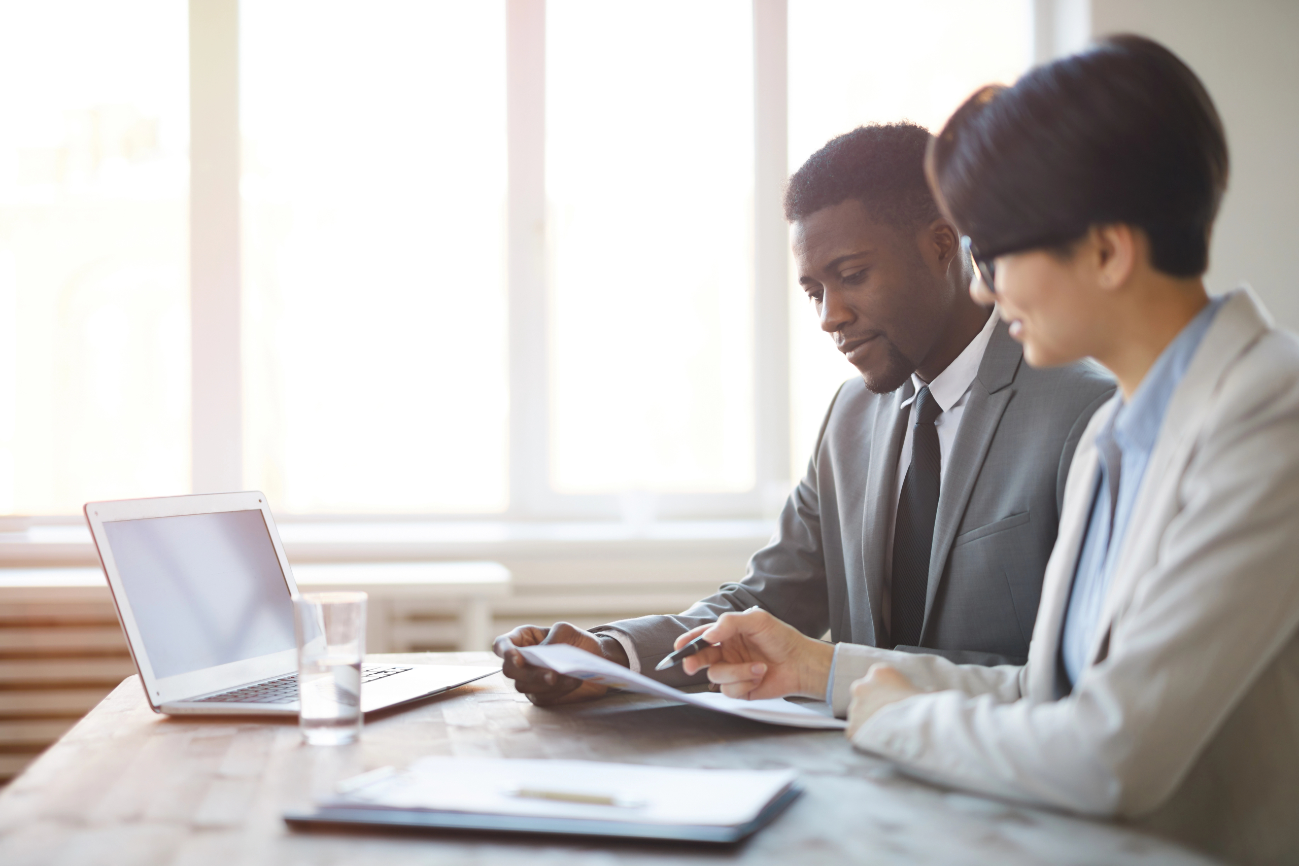 coworkers sit together at desk and work on sales funnel optimization