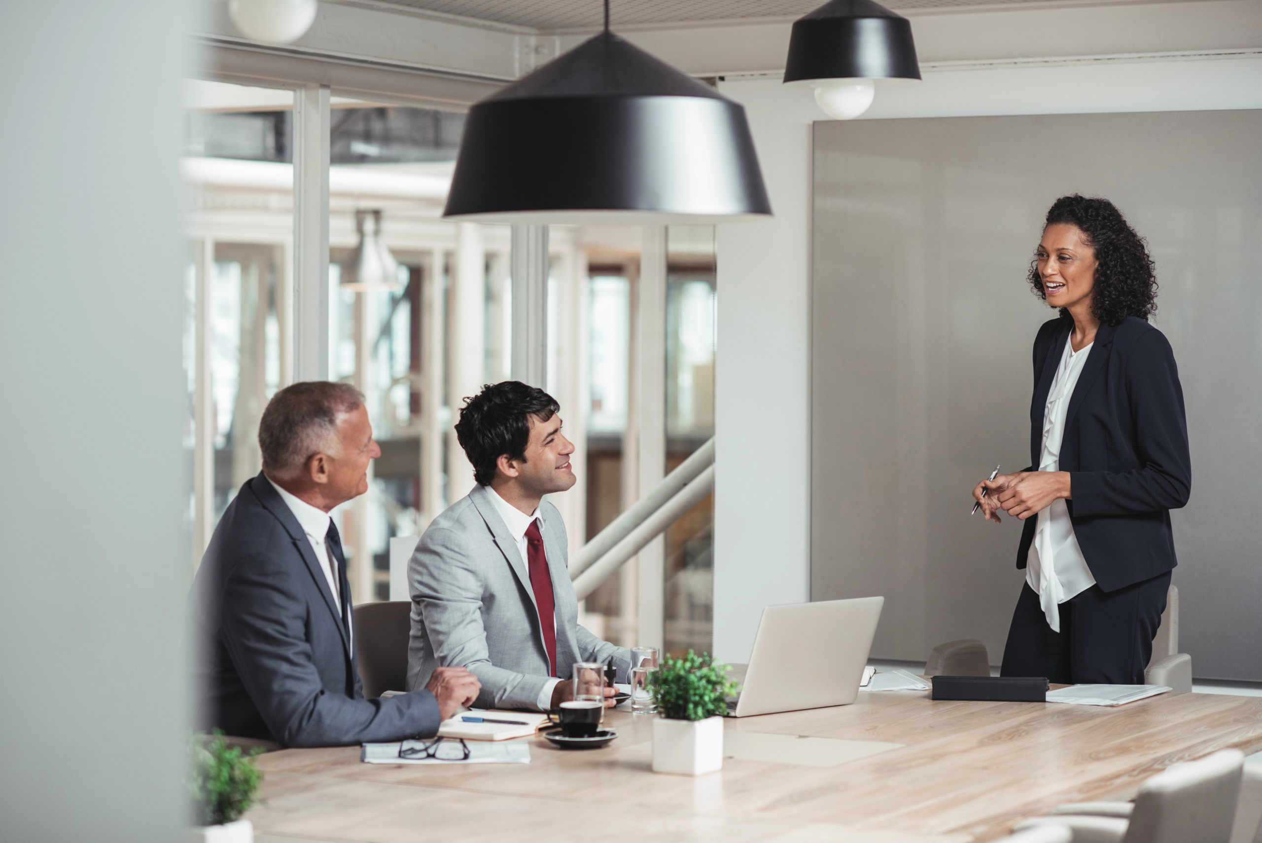 business woman standing in boardroom discussing b2b sales outsourcing with colleagues